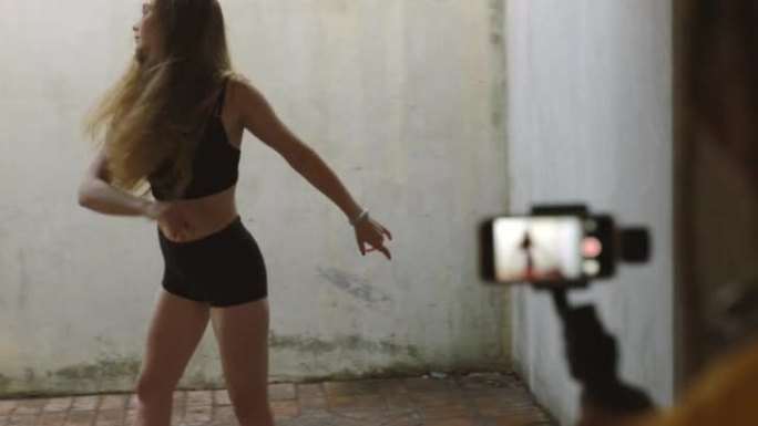影响者跳舞，在垃圾美学中通过智能手机视频制作社交媒体内容。具有健康，健身和活力的实时流媒体摄像师女性