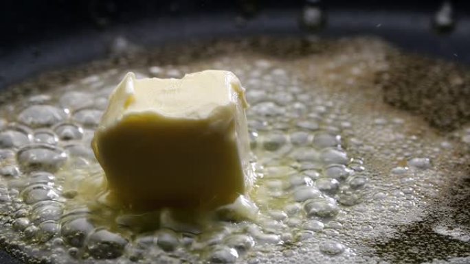 黄油在炉子上的煎锅里融化嘶嘶作响。特写。