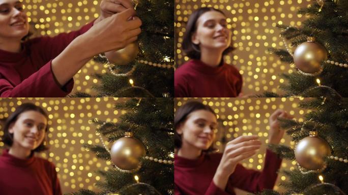 一个穿着红色毛衣的漂亮女孩将一个金色的圣诞节玩具挂在圣诞树上，只有树枝上的玩具在焦点上