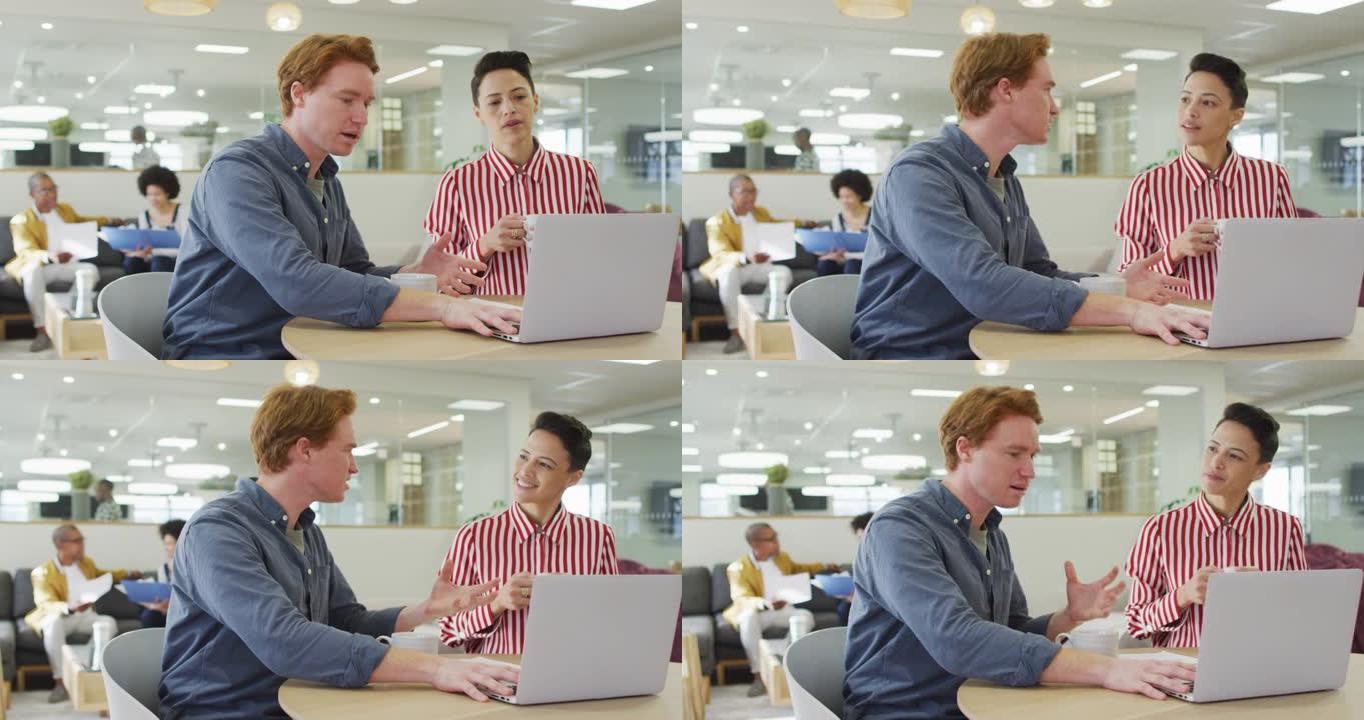 坐在办公桌前，使用笔记本电脑，在办公室进行商务谈话的男女同事