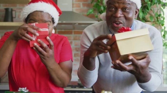 圣诞节时戴着圣诞老人帽子的快乐非裔美国高级夫妇在视频通话中赠送礼物