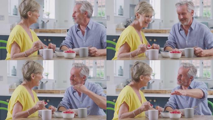 退休夫妇坐在家里的桌子旁，一起吃健康的早餐和新鲜水果