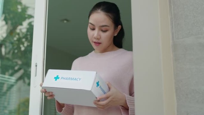 年轻的亚洲妇女收到药品药房医药箱送货上门。