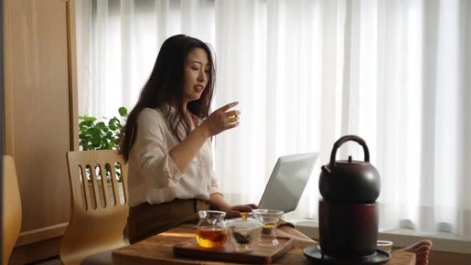 亚洲妇女在家喝茶时工作