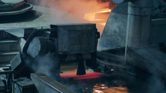 工业机器正在将金属板运送到热水中