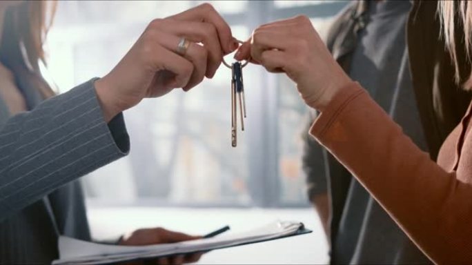 买卖房地产概念。男人和女人的特写手从房地产经纪人那里拿走了新的公寓钥匙。