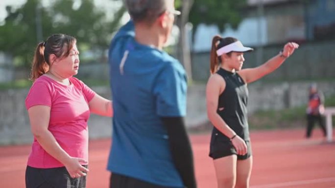 多元化亚洲华人社区热身运动上午在田径场跑步前