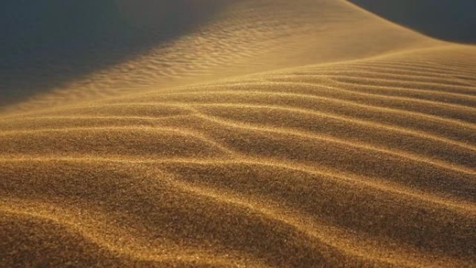 沙漠沙丘中的沙子随风飘动。沙粒沿着沙丘移动。沙漠中的日落。慢动作镜头