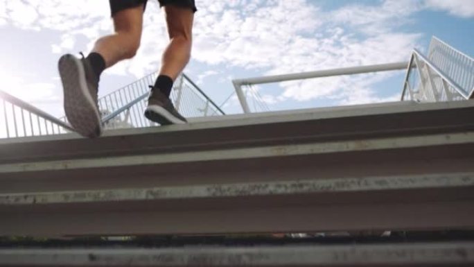 运动的男性在桥上的台阶上锻炼，锻炼身体并建立有氧耐力。适合在城市楼上跑步的运动员。市区户外慢跑的健康