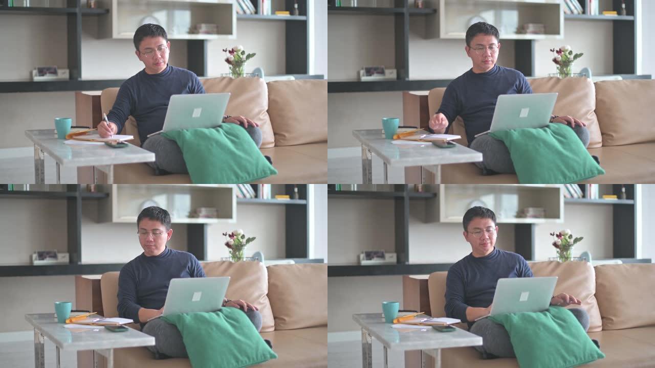 亚洲中国男性在家工作，在客厅沙发上使用笔记本电脑视频通话