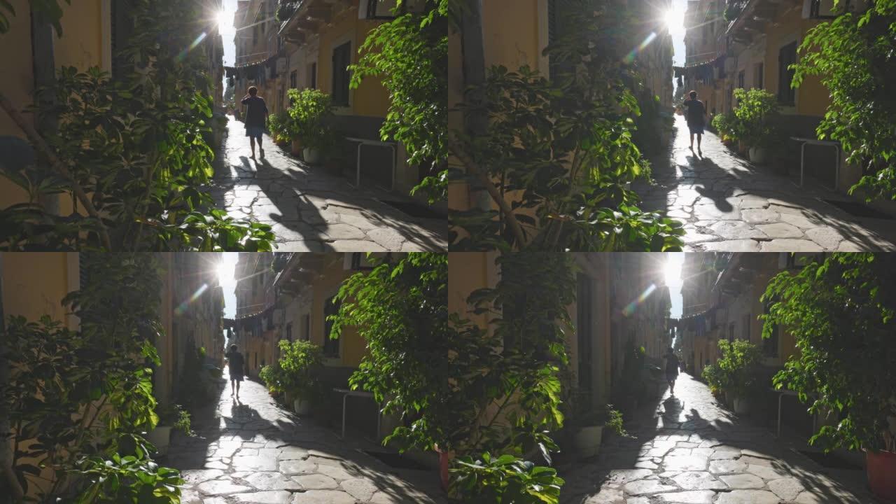 面目全非的女人走在希腊科孚岛Kerkyra的老房子之间的鹅卵石街道上。老城区狭窄的街道。科孚岛的当地