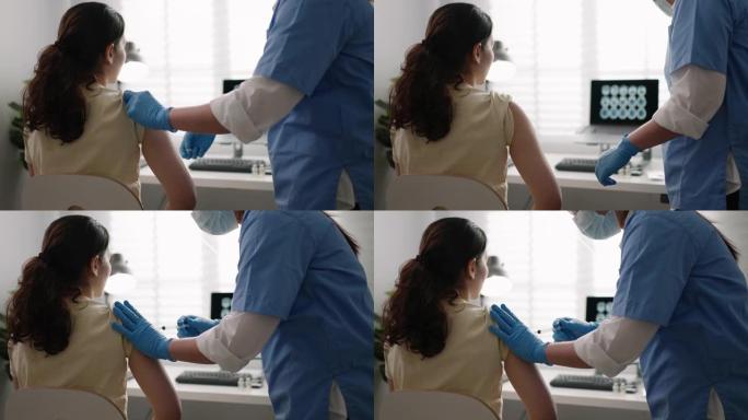戴着安全手套和防护口罩的护士正在健康诊所向女性患者注射疫苗