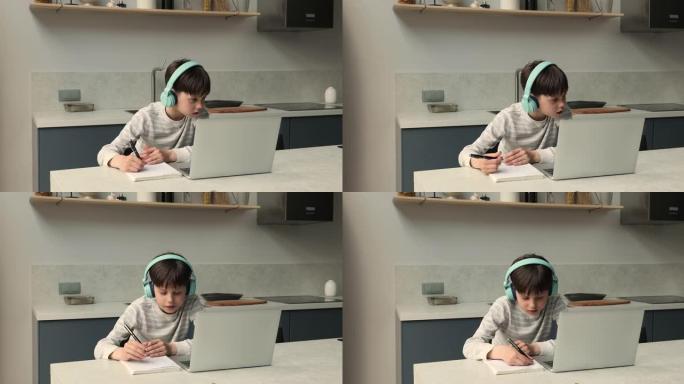 男生戴着耳机在家使用笔记本电脑在线学习