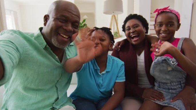 非裔美国人的祖父母和孙子在家里用智能手机拍摄视频时挥手致意