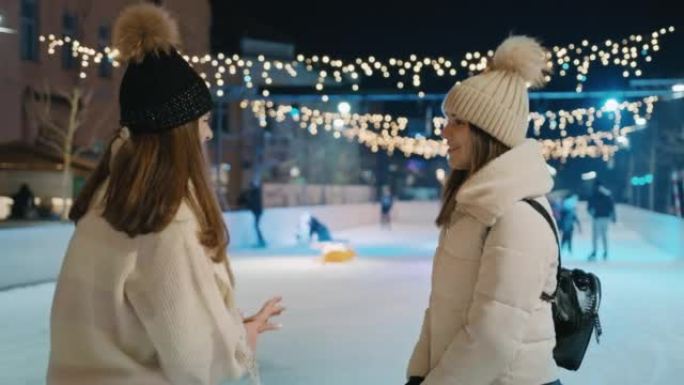 两名年轻女子晚上站在溜冰场上聊天