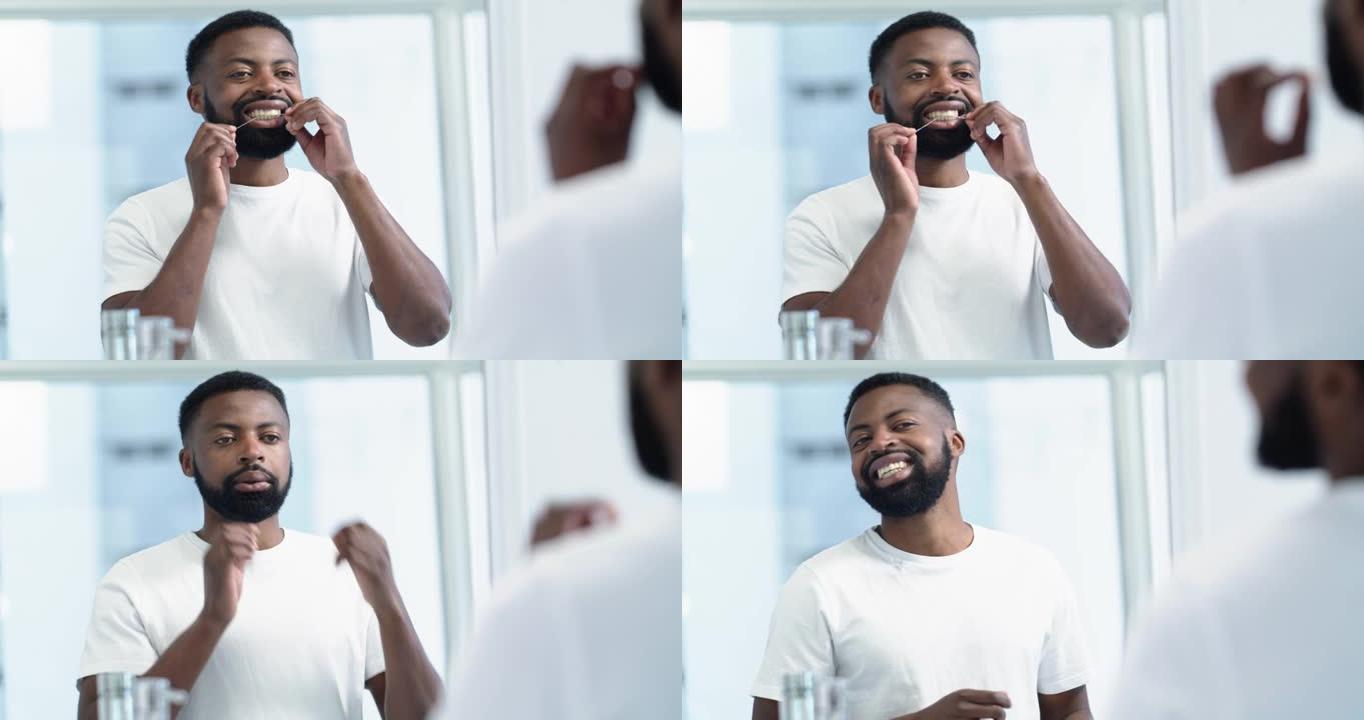 4k视频片段，一个英俊的年轻人在浴室里使用牙线作为他早上在家中的日常活动的一部分