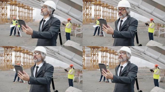 建筑师通过平板电脑进行在线视频通话，并看着站在建筑工地的显示器