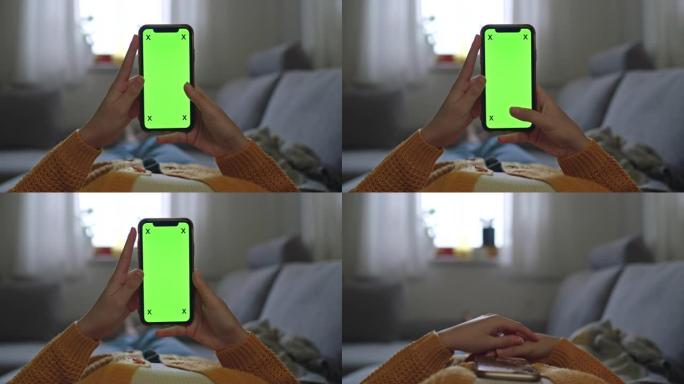 女士无法辨认的女人在家里的沙发上使用带有色度屏幕的智能手机