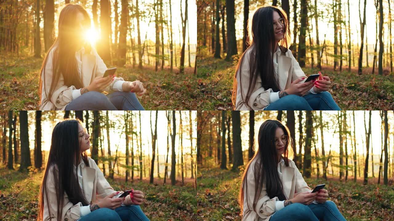 年轻女子坐在森林里，在森林里使用手机
