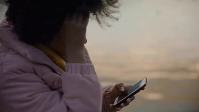 黑人女士在河边使用智能手机时看起来很担心