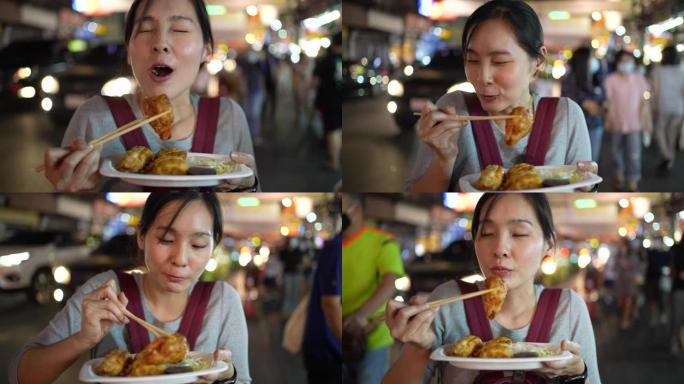 年轻的亚洲妇女在街上吃街头食物