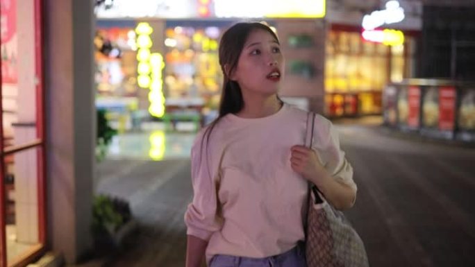 年轻的亚洲女性走在夜城街上