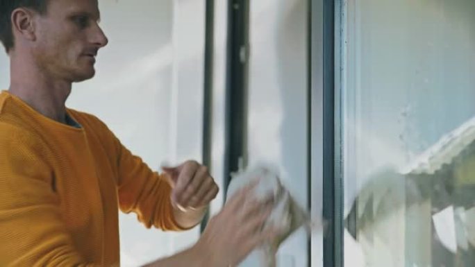 清洁工女士在擦拭玻璃露台门上的水滴时检查时间