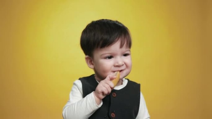 一个可爱的漂亮婴儿在吃柠檬。一个孩子品尝生柠檬。顽皮的小男孩吃水果。抱着吃的美味的小孩。有趣的表达情