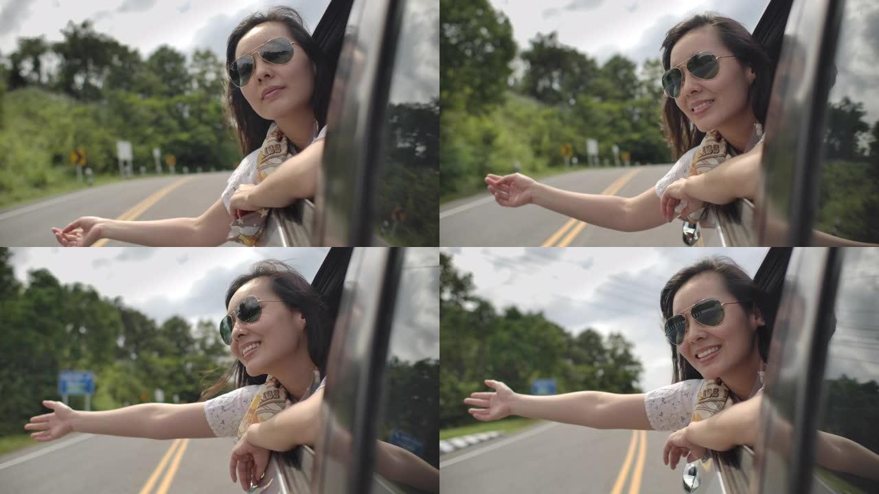 亚洲妇女坐在一辆车里，抱着胳膊离开车窗，享受着乐趣，在公路旅行中享受着乐趣
