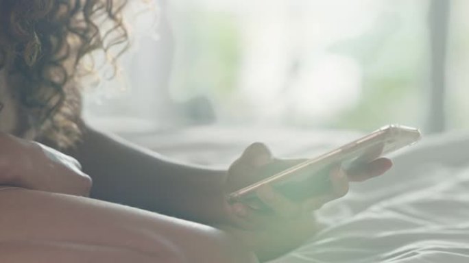 一名妇女在家中床上使用智能手机的4k视频片段