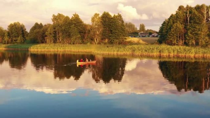 无人机飞向幸福的家庭，孩子们一起享受划船的乐趣，在令人难以置信的夏季日出静止湖。