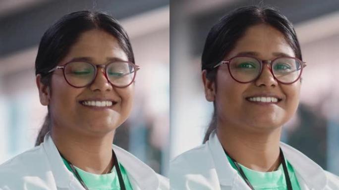 垂直屏幕: 年轻的印度女专家穿着实验室外套和眼镜微笑的肖像特写。在大学实验室担任工程师，理科学生的职