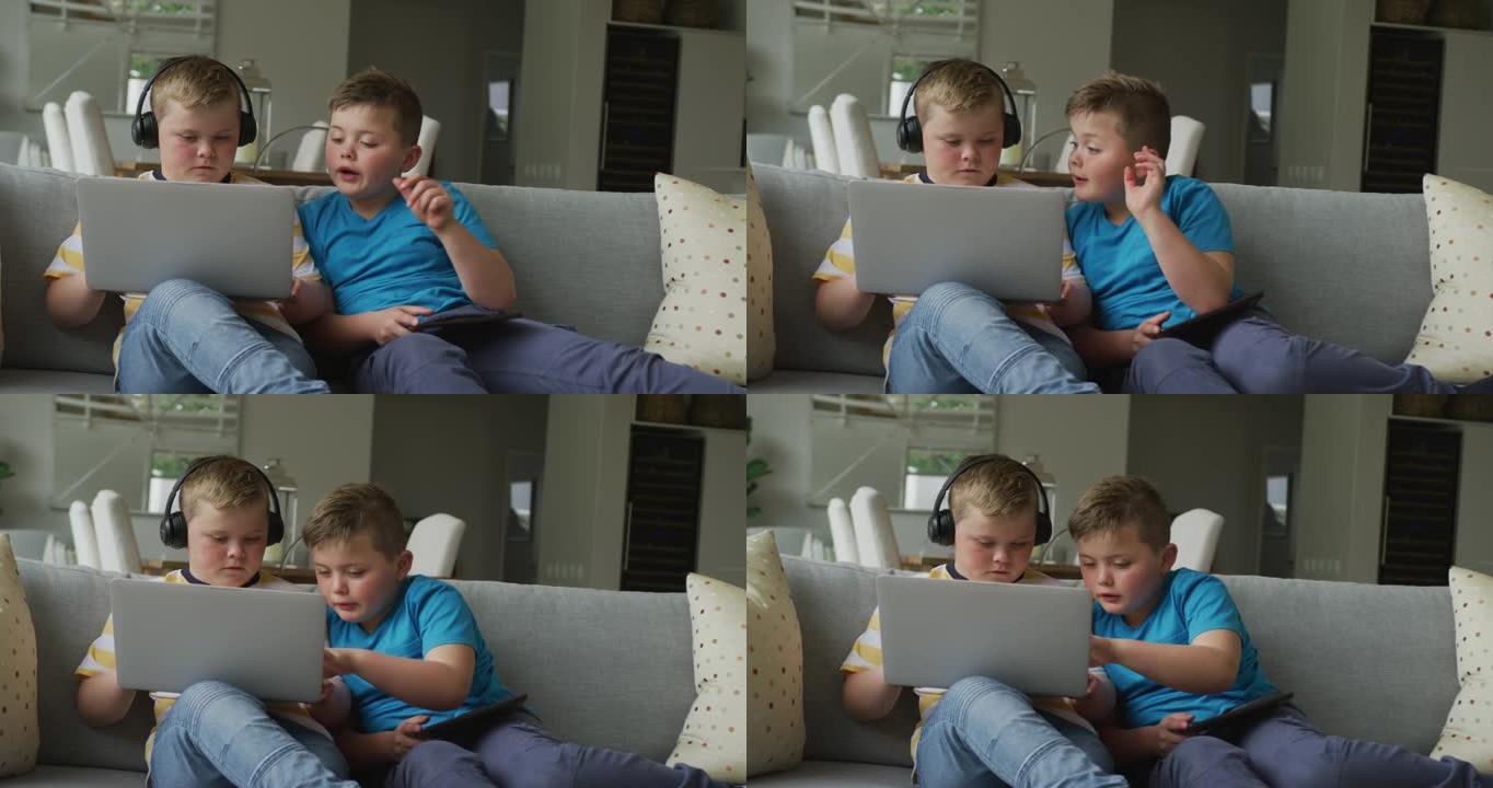 高加索男孩和他的兄弟坐在客厅并使用笔记本电脑