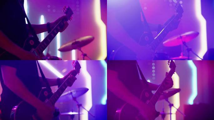 摇滚乐队在夜总会的音乐会上表演。音乐家演奏的六弦吉他的特写镜头。舞台上明亮多彩的频闪灯前的现场音乐派