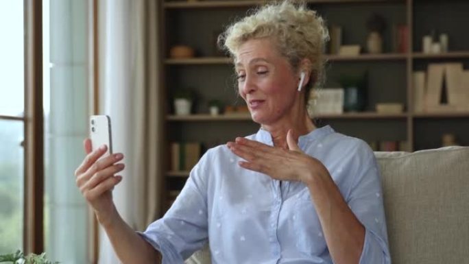 Attractive older woman in wireless earphones talks