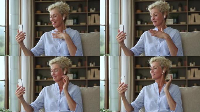 Attractive older woman in wireless earphones talks