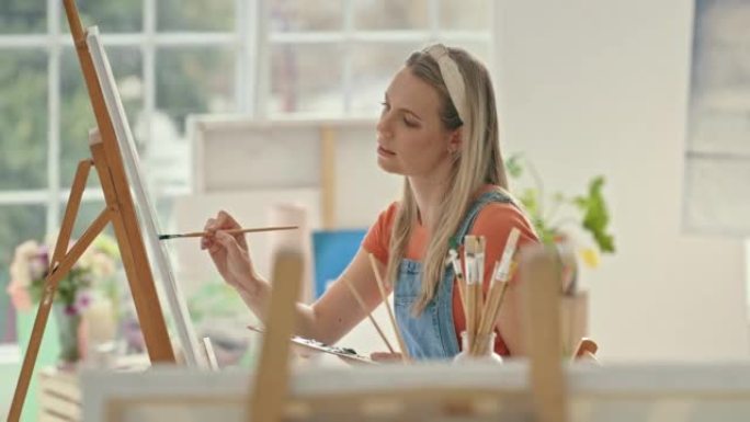 创意女艺术家在艺术工作室里画一个形象。艺术画家在画布上使用画笔创作一幅画。年轻的设计师在周末在家做她