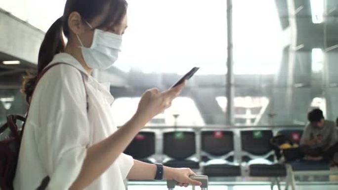 亚洲妇女在机场柜台使用智能手机时戴口罩