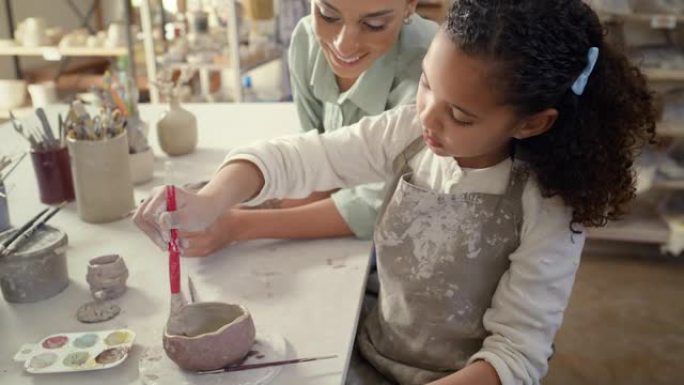 陶瓷班，车间里的女人和孩子画碗，创意课和工艺工作室，用于技能，创造力或学习。美术课上的年轻女孩，儿童