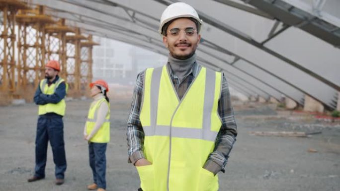 戴着安全帽和背心站在建筑工地的阿拉伯男子的慢动作肖像