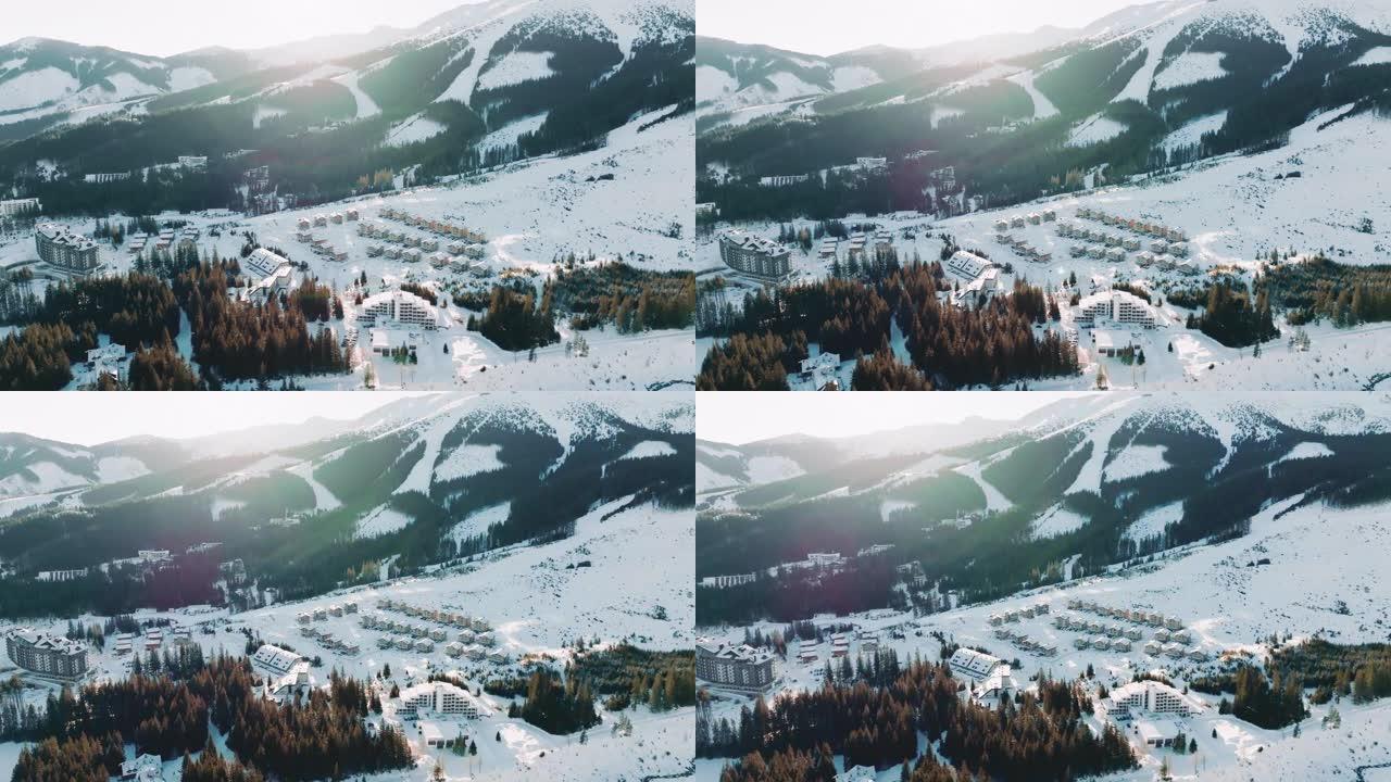 滑雪胜地全景田园诗般的冬季村庄，木屋建筑在寒冷阳光明媚的早晨雪山中拍摄。
