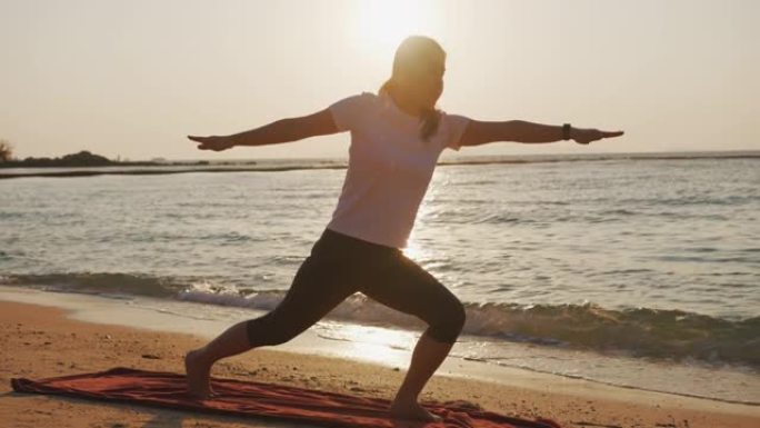 女人在户外日落时在大自然中摆树瑜伽姿势。张开双臂的运动瑜伽女子在海水海滩练习瑜伽