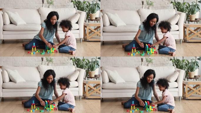 非裔美国母亲和学龄前的女儿在地板上玩构造游戏