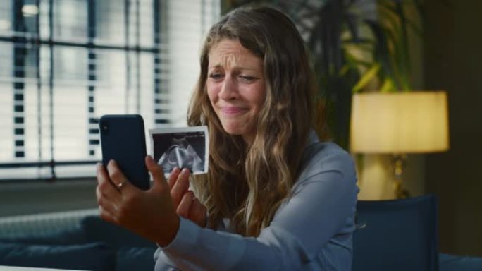 一名年轻孕妇的电影慢动作特写镜头正在给她的亲戚或朋友打视频，并显示超声波以宣布她未来的孩子出生。