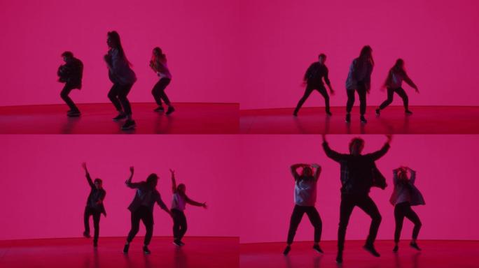 由三位时尚的专业舞者组成的多元化小组，在工作室环境中的虚拟制作过程中，在带有粉红色背景的大Led墙屏