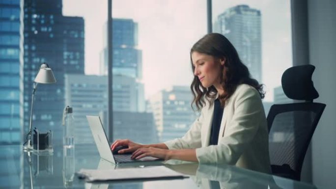 年轻成功的白人女商人坐在办公桌前在城市办公室的笔记本电脑上工作的肖像。雄心勃勃的公司经理计划电子商务