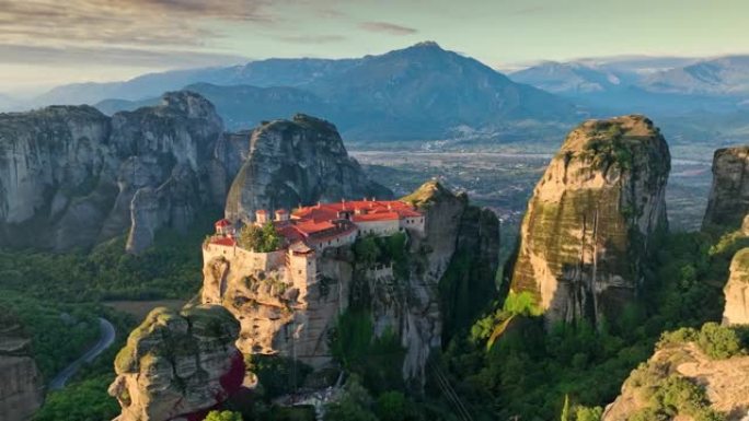 希腊，日出时飞越迈泰奥拉修道院。风景秀丽，有青山、岩石和古老的寺庙。鸟瞰图，4K