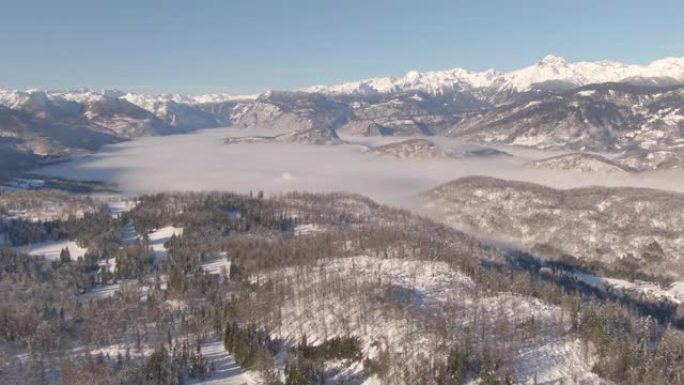 空中: 雾蒙蒙的山谷和白雪皑皑的朱利安阿尔卑斯山的美丽鸟瞰图。
