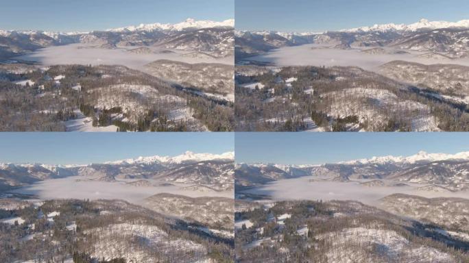 空中: 雾蒙蒙的山谷和白雪皑皑的朱利安阿尔卑斯山的美丽鸟瞰图。
