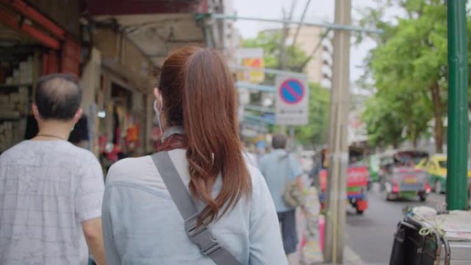 亚洲成年妇女在当地旅游场所散步和购物。迷人的女性在当地旅行时寻找街头美食。单人旅行者概念。